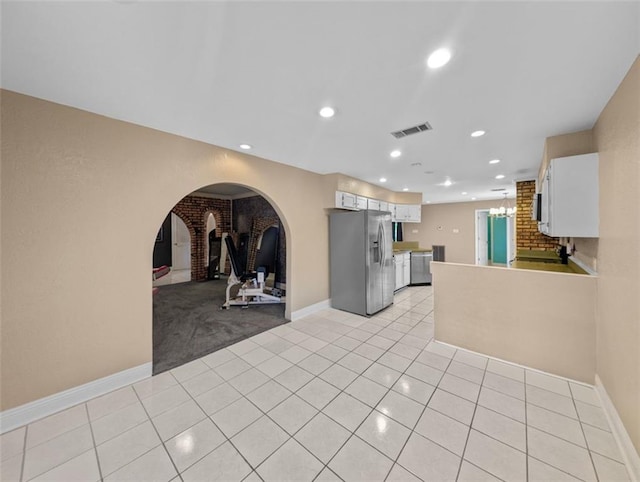 kitchen featuring white cabinets, kitchen peninsula, light tile patterned floors, and stainless steel appliances