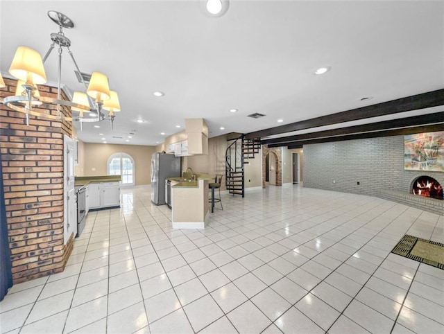 kitchen with pendant lighting, white cabinets, a kitchen breakfast bar, a fireplace, and brick wall