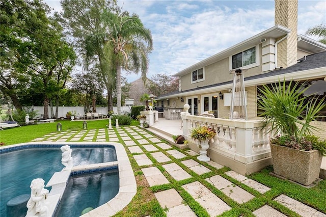 rear view of house with a swimming pool with hot tub, exterior bar, a lawn, and a patio area