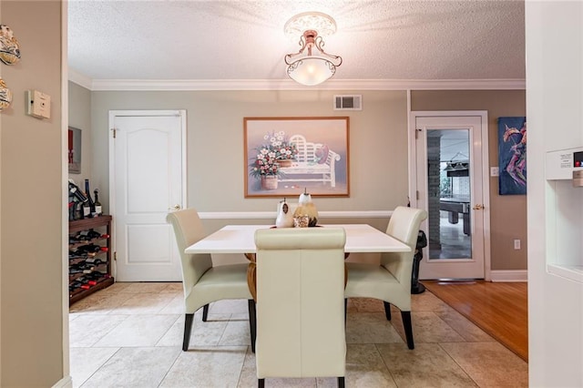 tiled dining area featuring crown molding and a textured ceiling