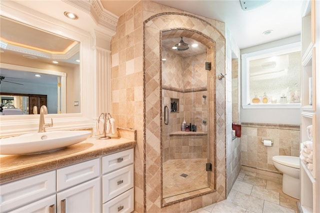 bathroom with vanity, toilet, an enclosed shower, and tile walls