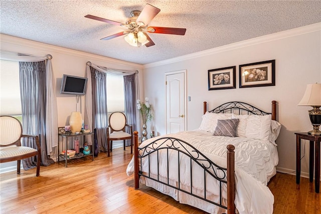 bedroom featuring ceiling fan, ornamental molding, light hardwood / wood-style flooring, and a textured ceiling