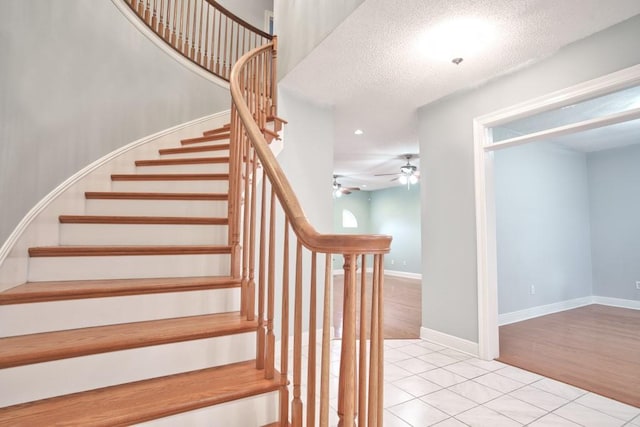 staircase featuring ceiling fan, tile patterned floors, and a textured ceiling