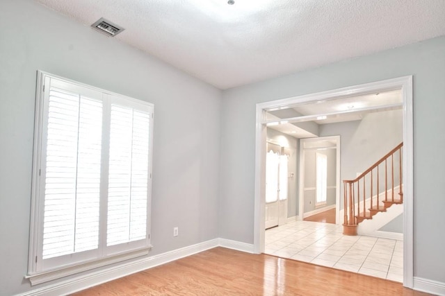 unfurnished room with light hardwood / wood-style flooring and a textured ceiling