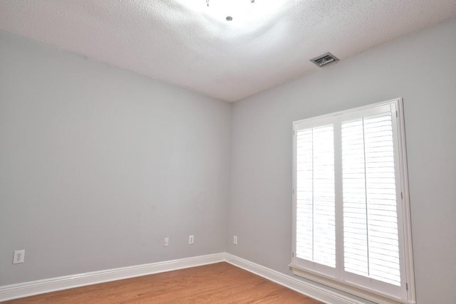 unfurnished room featuring wood-type flooring and a textured ceiling