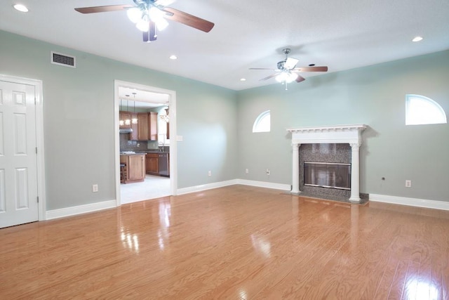 unfurnished living room with ceiling fan, a high end fireplace, and light hardwood / wood-style flooring