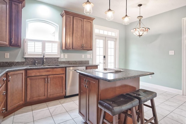 kitchen with a kitchen island, decorative light fixtures, dishwasher, sink, and a breakfast bar area