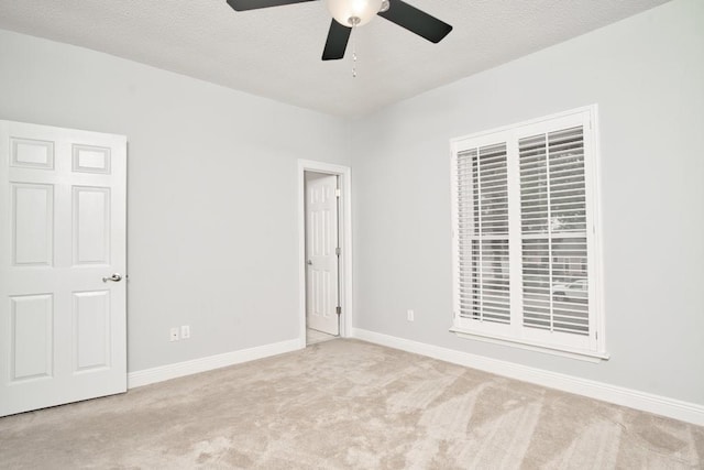 unfurnished bedroom featuring light colored carpet, a textured ceiling, and ceiling fan