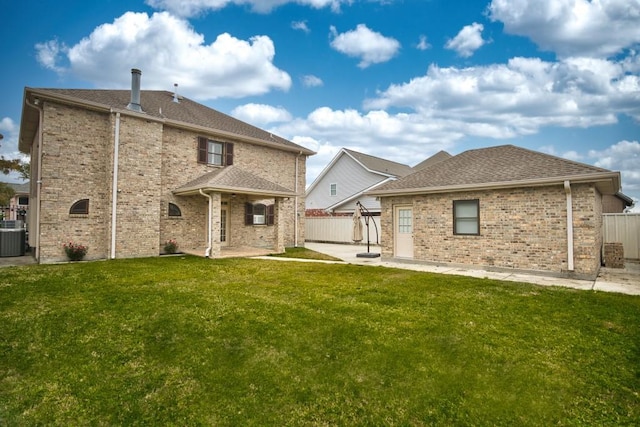 rear view of house with central AC, a patio area, and a lawn