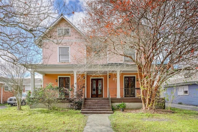 view of front of property featuring covered porch, french doors, and a front yard