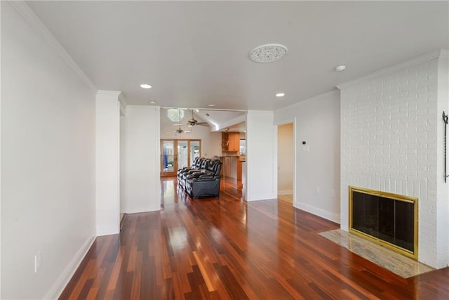 living room featuring crown molding, ceiling fan, a fireplace, and dark wood-type flooring