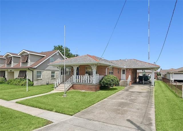 view of front of home featuring brick siding, roof with shingles, covered porch, a front yard, and driveway