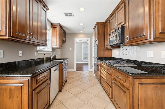 kitchen with dark stone countertops, light tile patterned floors, sink, and appliances with stainless steel finishes