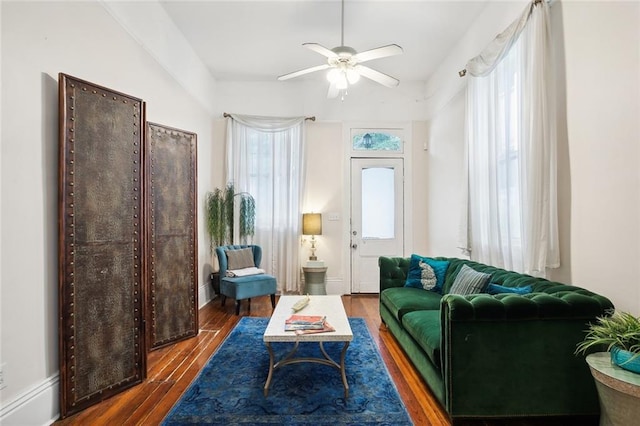 sitting room with ceiling fan and dark wood-type flooring