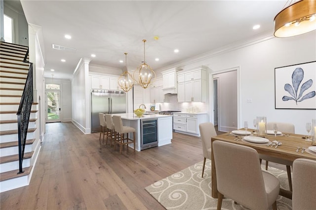 kitchen with a center island, white cabinets, hanging light fixtures, wine cooler, and appliances with stainless steel finishes