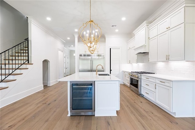 kitchen featuring decorative light fixtures, high quality appliances, white cabinetry, and beverage cooler