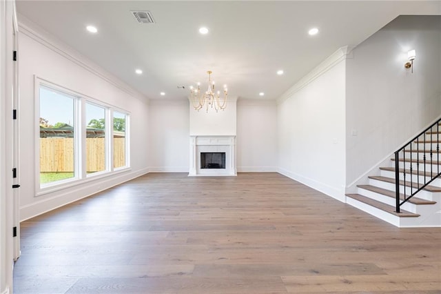 unfurnished living room featuring hardwood / wood-style floors, ornamental molding, and a notable chandelier