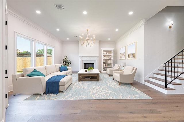 living room with light wood-type flooring, ornamental molding, and a chandelier