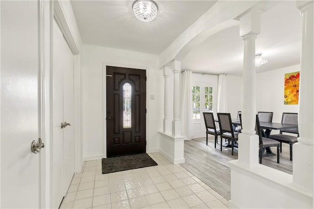 tiled foyer featuring a notable chandelier and ornate columns