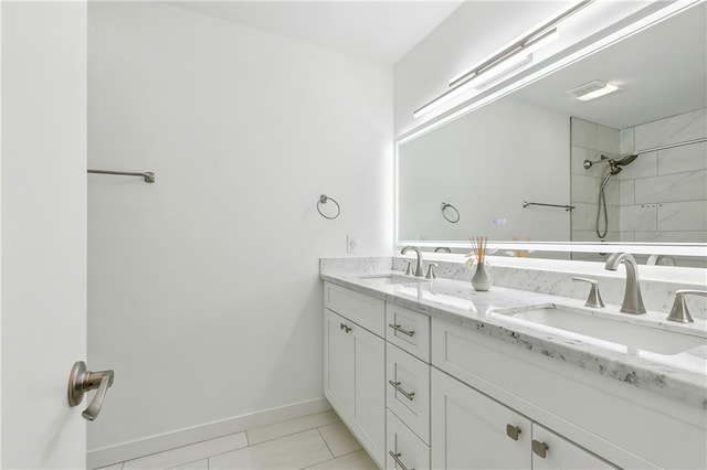 bathroom with tiled shower, vanity, and tile patterned flooring