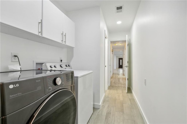 washroom featuring cabinets, light wood-type flooring, and washing machine and dryer