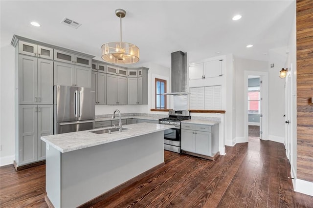 kitchen featuring sink, hanging light fixtures, stainless steel appliances, wall chimney range hood, and light stone counters