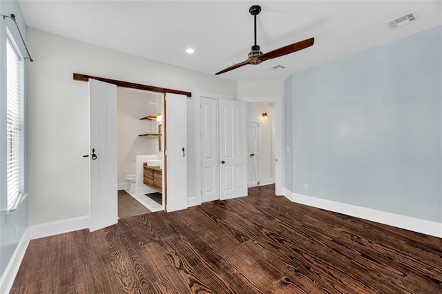 unfurnished bedroom featuring ensuite bath, ceiling fan, and dark hardwood / wood-style floors