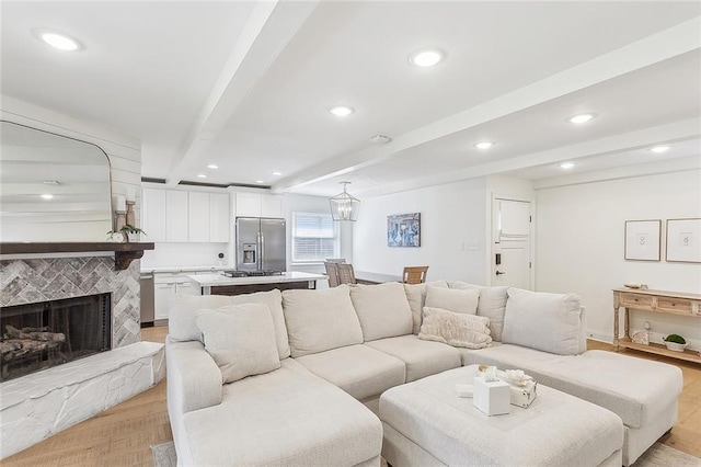 living room with beam ceiling and a stone fireplace