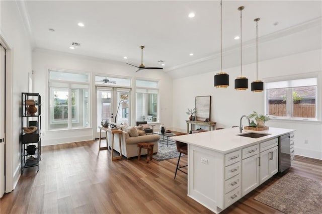 kitchen featuring ceiling fan, sink, pendant lighting, a kitchen island with sink, and white cabinets