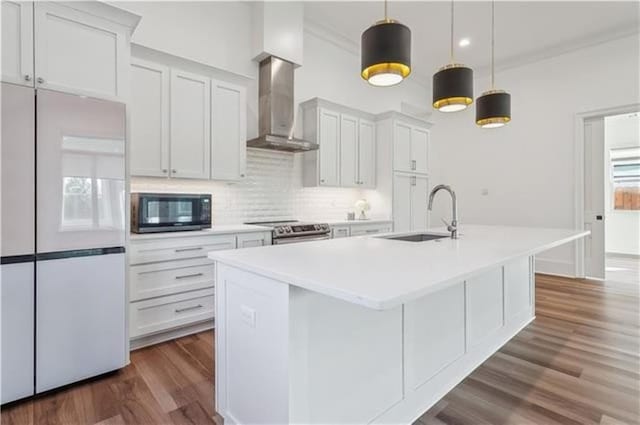 kitchen featuring wall chimney exhaust hood, white fridge, white cabinetry, and sink