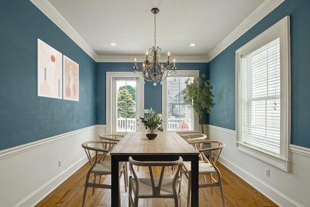 dining space with a notable chandelier, wood-type flooring, and ornamental molding