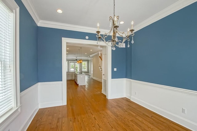 unfurnished dining area with hardwood / wood-style flooring, crown molding, sink, and a chandelier