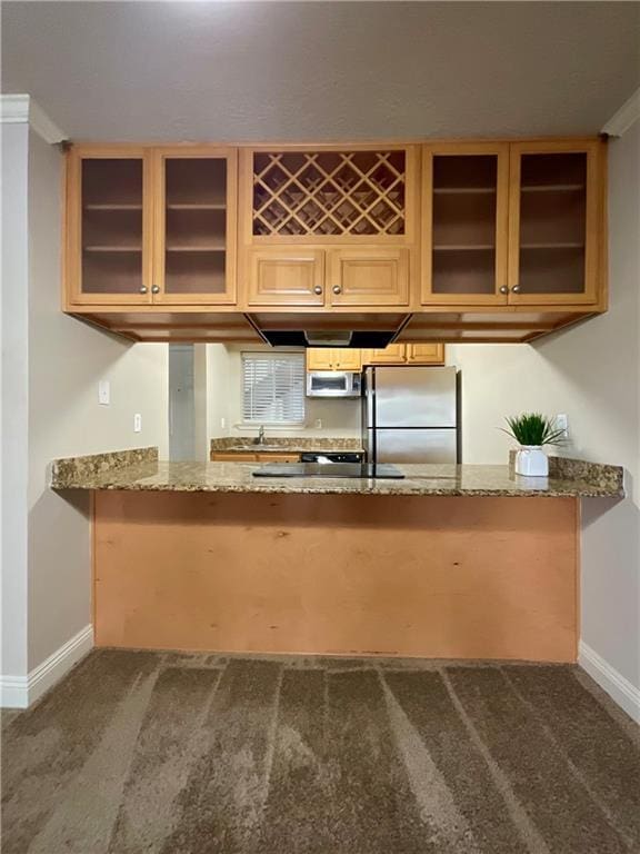 kitchen featuring stainless steel refrigerator, sink, dark colored carpet, light stone counters, and kitchen peninsula