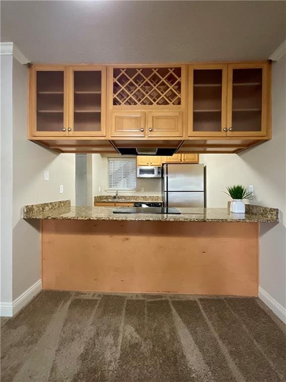 kitchen featuring glass insert cabinets, light stone counters, a peninsula, and stainless steel appliances