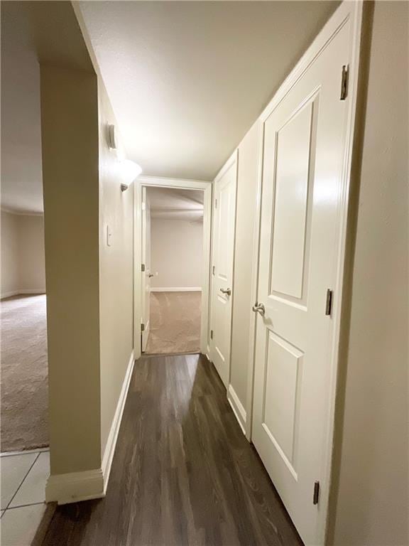 hall with carpet flooring, baseboards, and wood finished floors