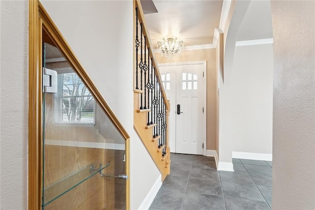 foyer entrance with dark tile patterned floors, ornamental molding, and a notable chandelier