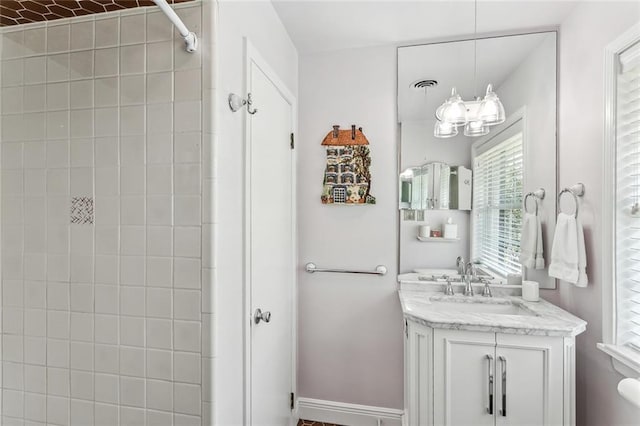 bathroom with a tile shower and vanity