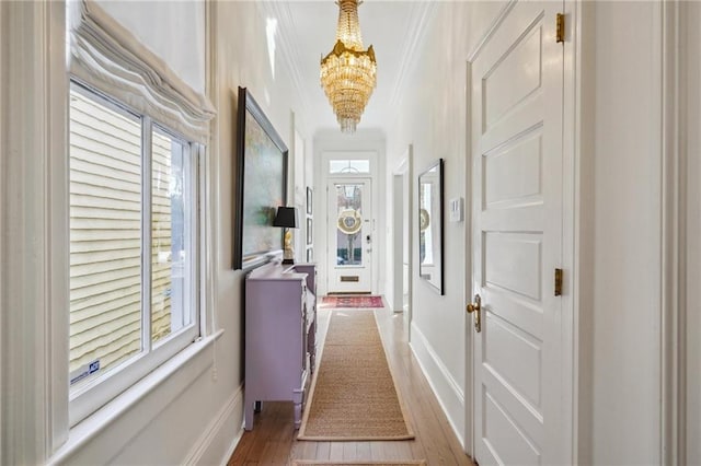 hall featuring crown molding, light hardwood / wood-style flooring, plenty of natural light, and an inviting chandelier