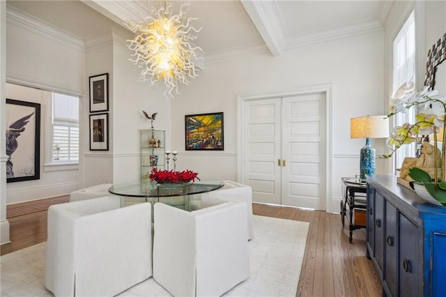 dining space with beamed ceiling, a notable chandelier, light hardwood / wood-style floors, and crown molding