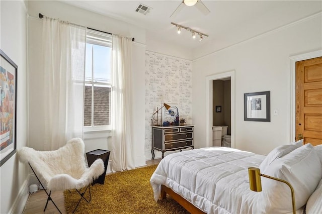 bedroom with connected bathroom, ceiling fan, hardwood / wood-style floors, and rail lighting