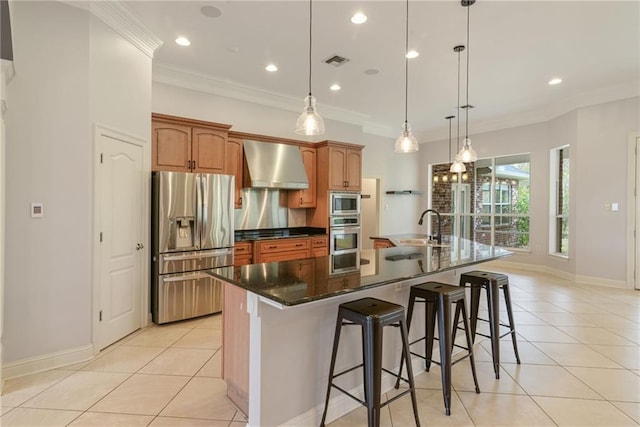 kitchen featuring a large island, wall chimney exhaust hood, pendant lighting, and stainless steel appliances