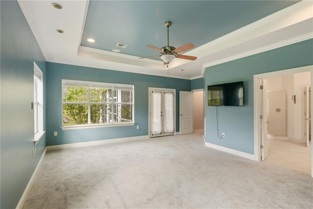 unfurnished bedroom with ceiling fan, a raised ceiling, light colored carpet, and crown molding