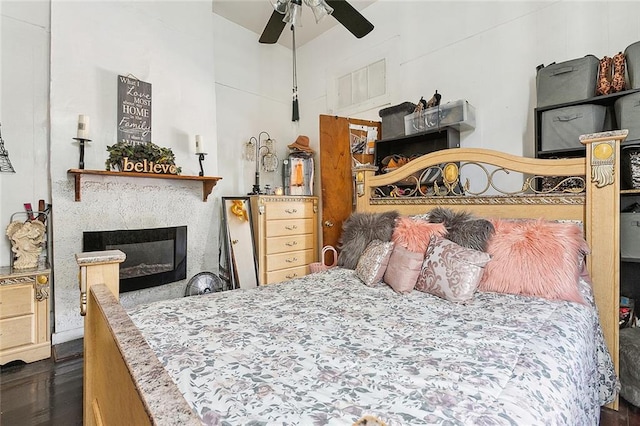 bedroom with ceiling fan, dark hardwood / wood-style floors, and a premium fireplace