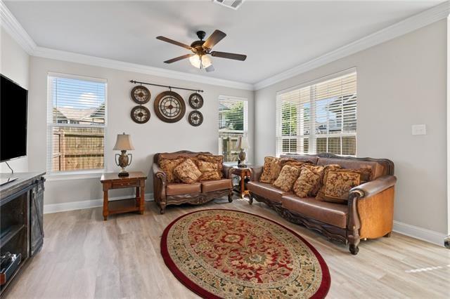 living room with ornamental molding, ceiling fan, and light wood-type flooring