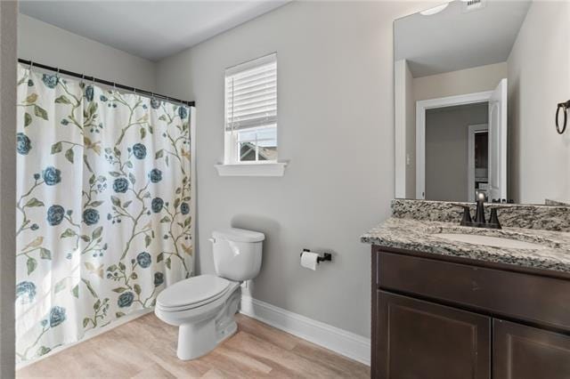 bathroom with hardwood / wood-style flooring, vanity, a shower with shower curtain, and toilet