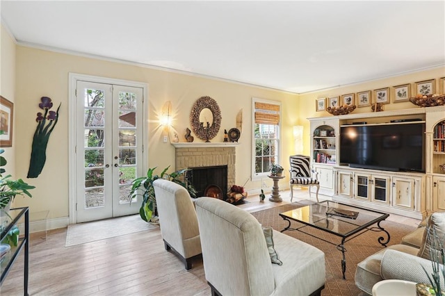 living room featuring light hardwood / wood-style flooring, french doors, crown molding, and a brick fireplace