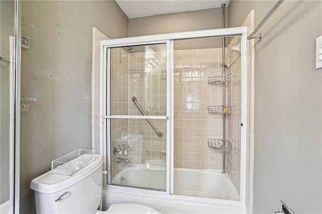 bathroom featuring toilet and shower / bath combination with glass door