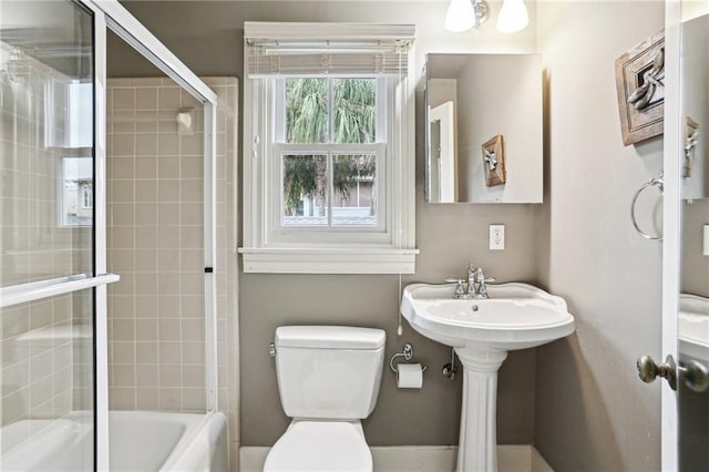 bathroom featuring toilet and bath / shower combo with glass door