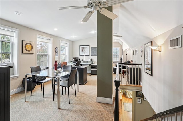 dining space featuring plenty of natural light, lofted ceiling, and light carpet