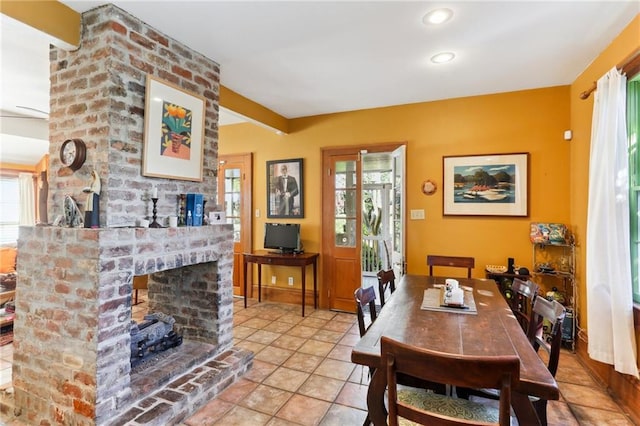 dining space with light tile patterned floors, a fireplace, and a healthy amount of sunlight